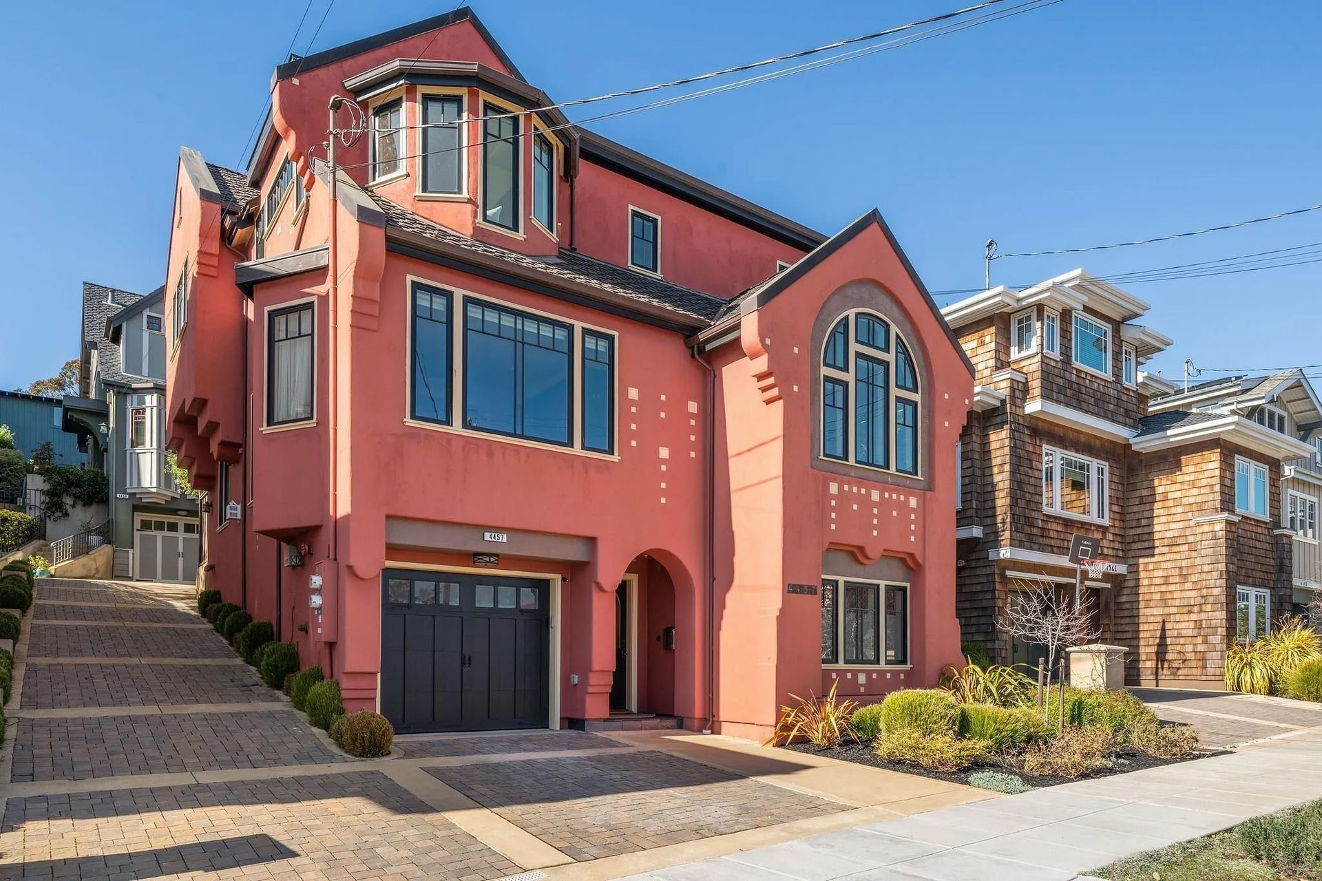 A large red house with a black garage door is sitting on top of a hill.