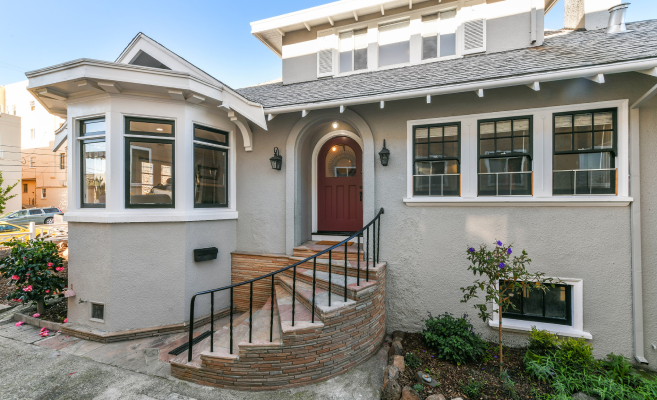 The front of a house with a red door and stairs leading up to it.