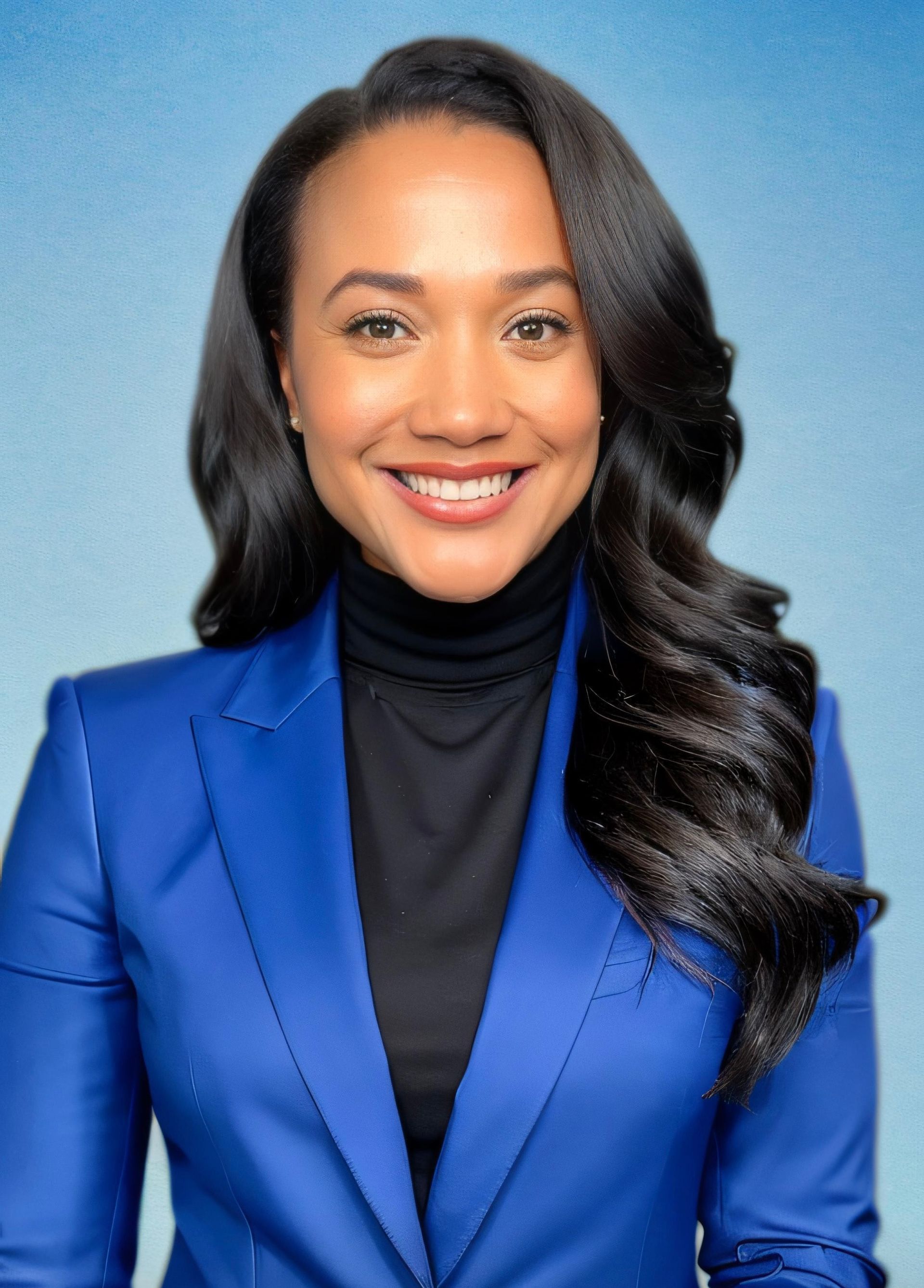 A woman wearing a blue jacket and black turtleneck smiles for the camera