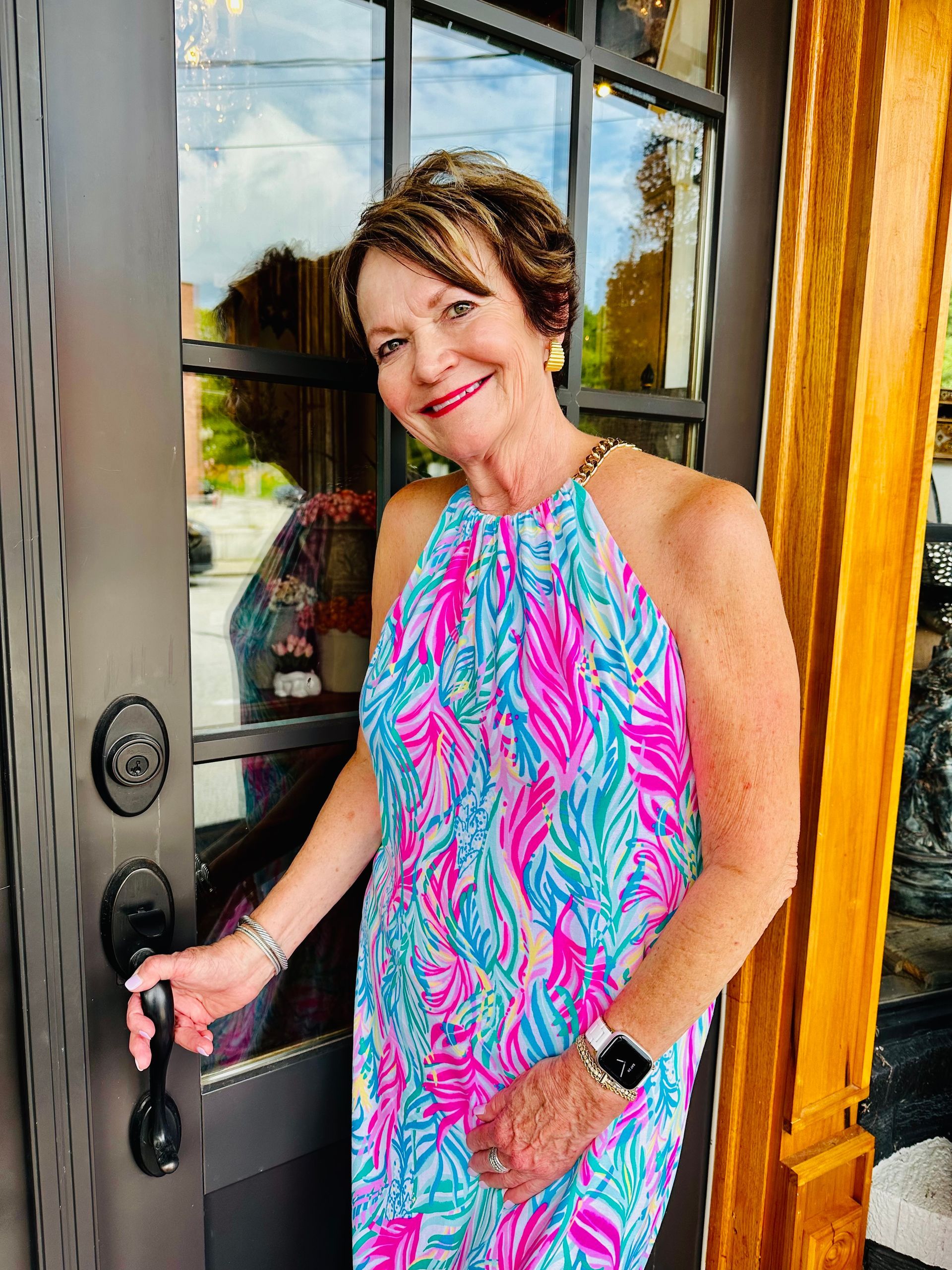 A woman in a colorful dress is standing in front of a door holding a key.
