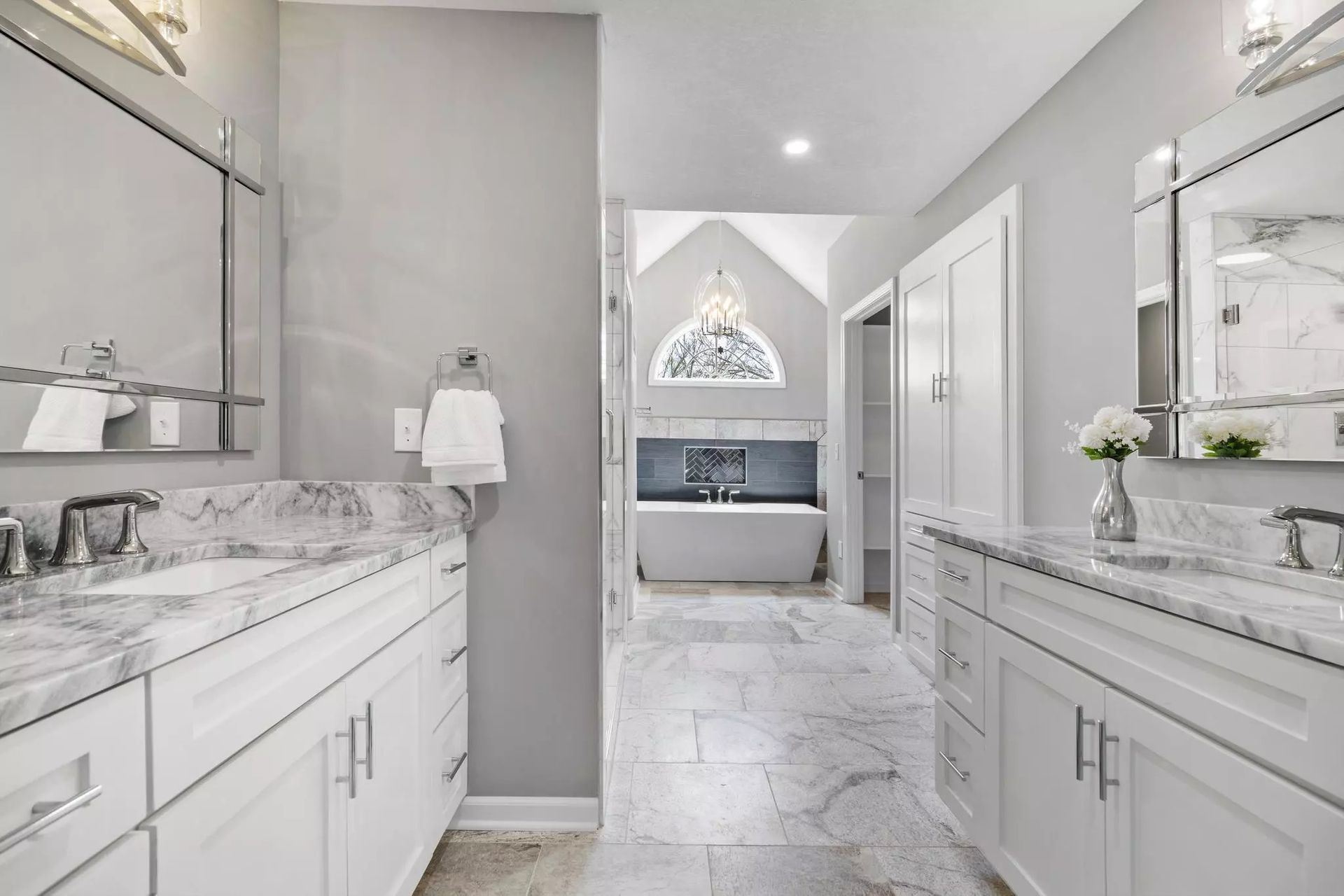 A bathroom with two sinks , two mirrors and a bathtub.