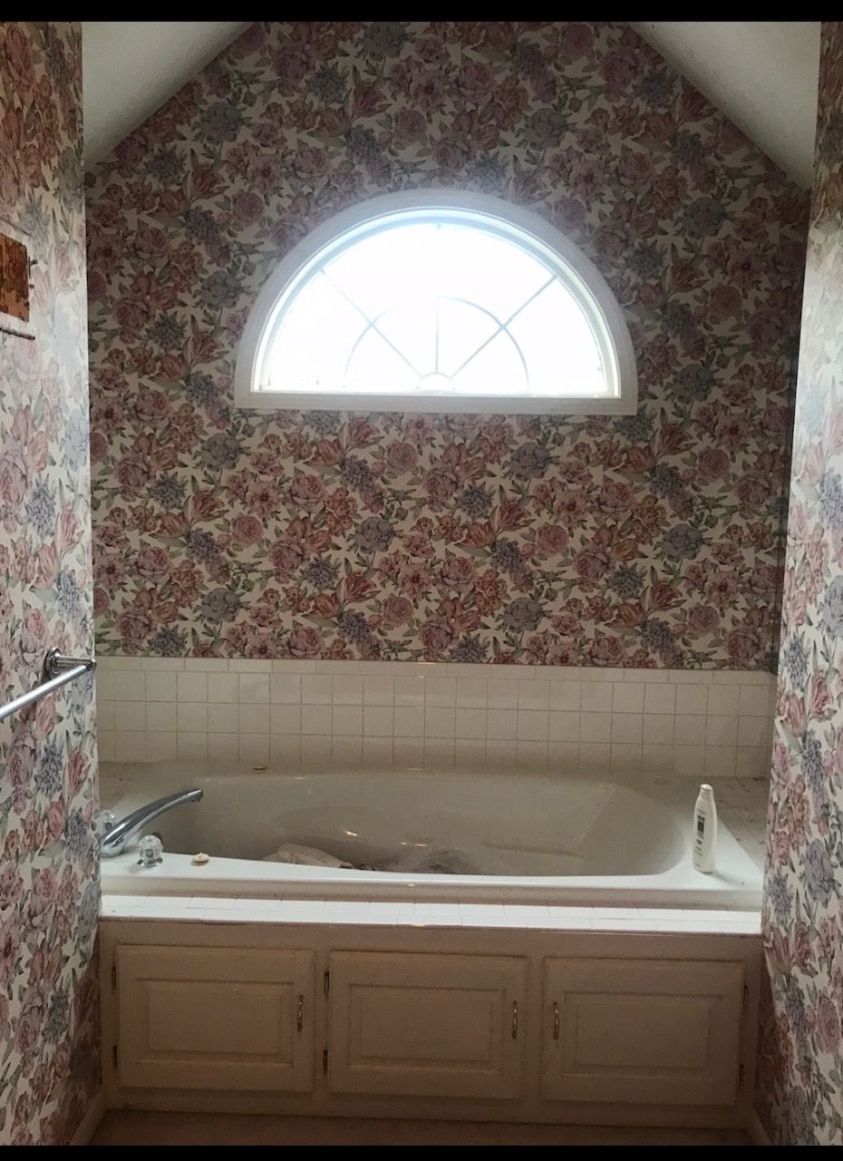 A bathroom with a bathtub and a window.