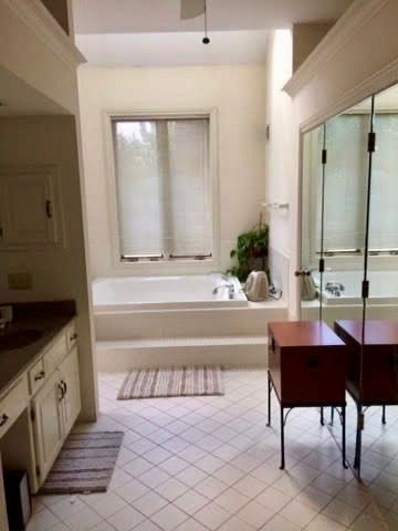A bathroom with a tub , sink , and mirrors.