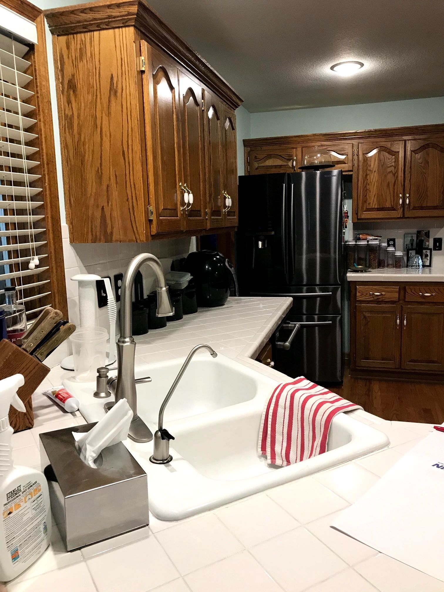 A kitchen with stainless steel appliances , wooden cabinets , a sink and a refrigerator.