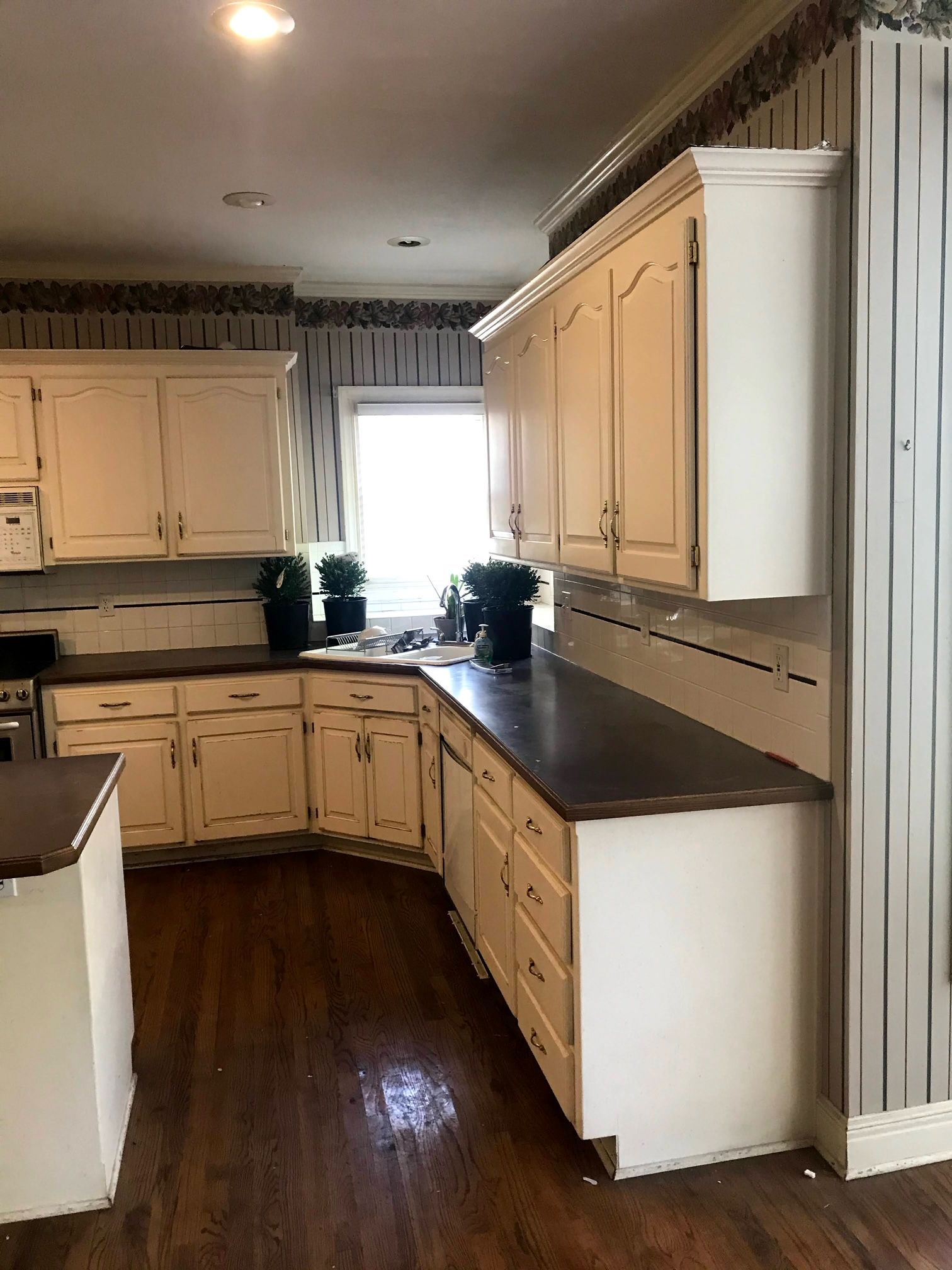 A kitchen with white cabinets and a wooden floor