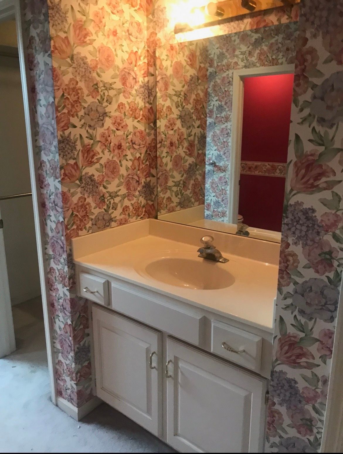 A bathroom with a sink , mirror and floral wallpaper