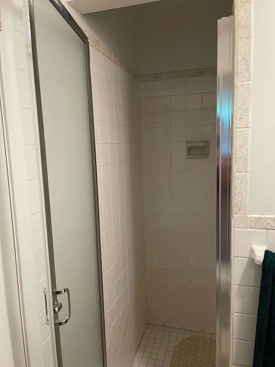 A bathroom with a walk in shower with a glass door.