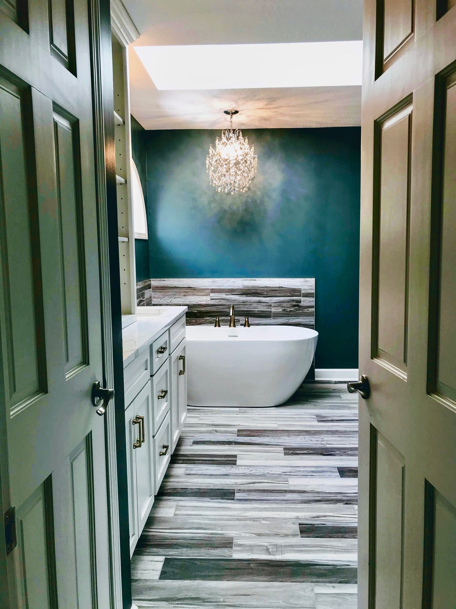 A bathroom with a tub , sink , and skylight.