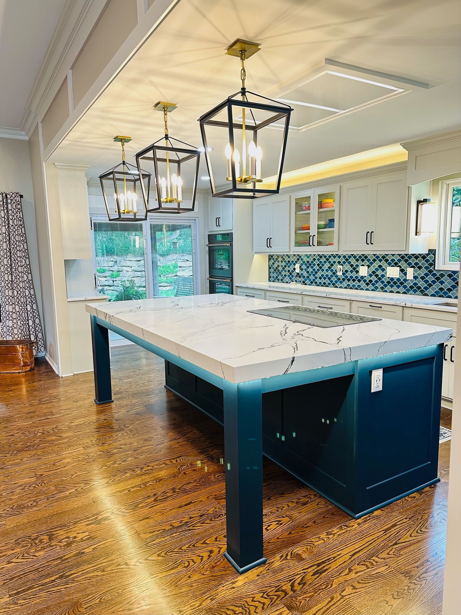 A kitchen with a large island and lanterns hanging from the ceiling.