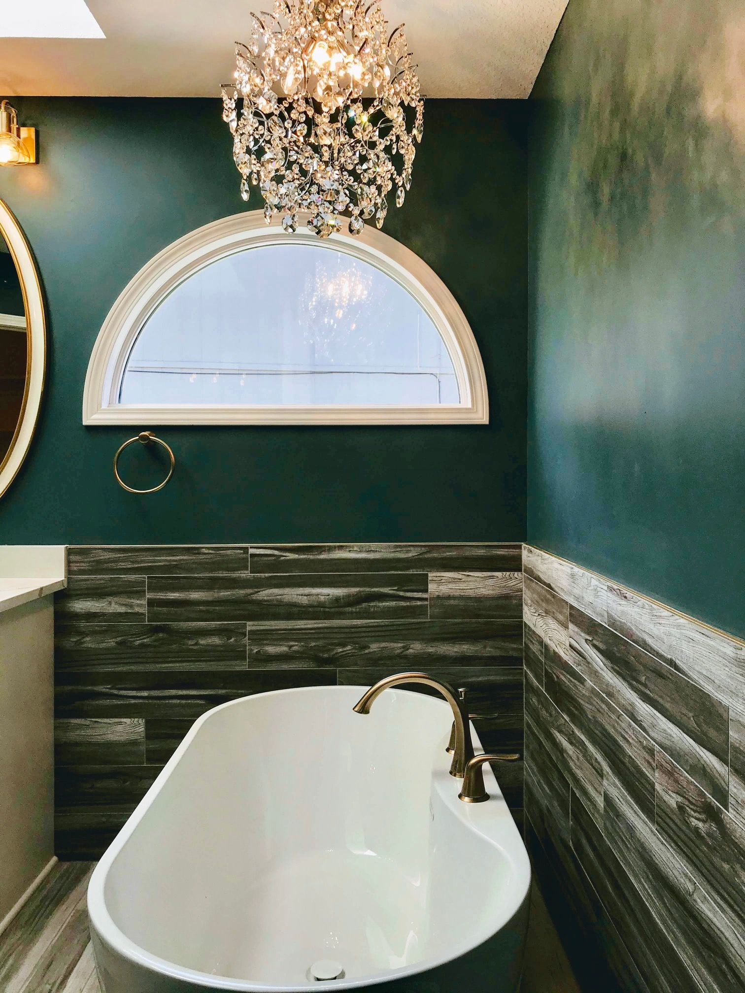 A bathroom with a bathtub and a chandelier hanging from the ceiling.