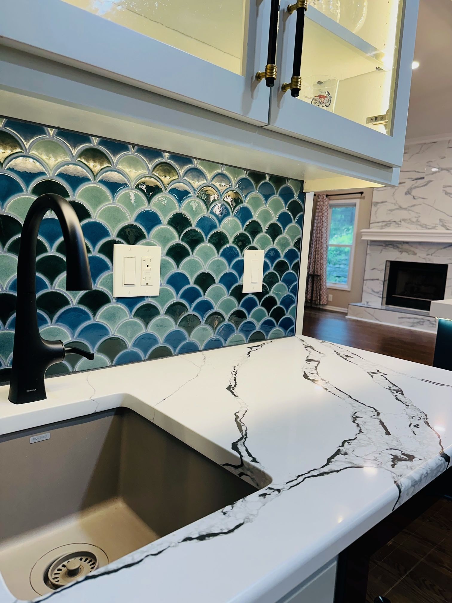 A kitchen with a sink and a mermaid tile wall