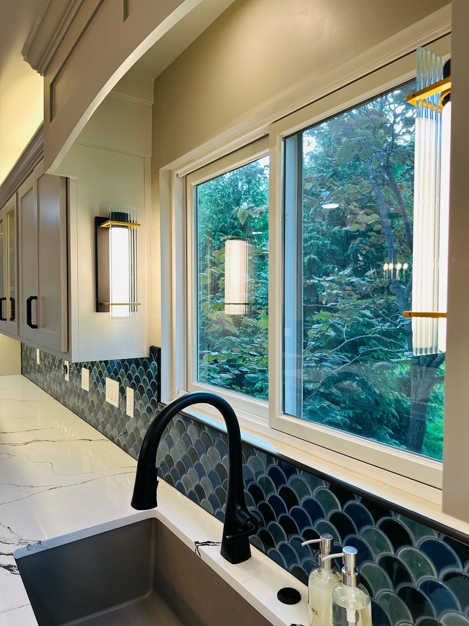 A kitchen with a sink and a window with trees in the background.