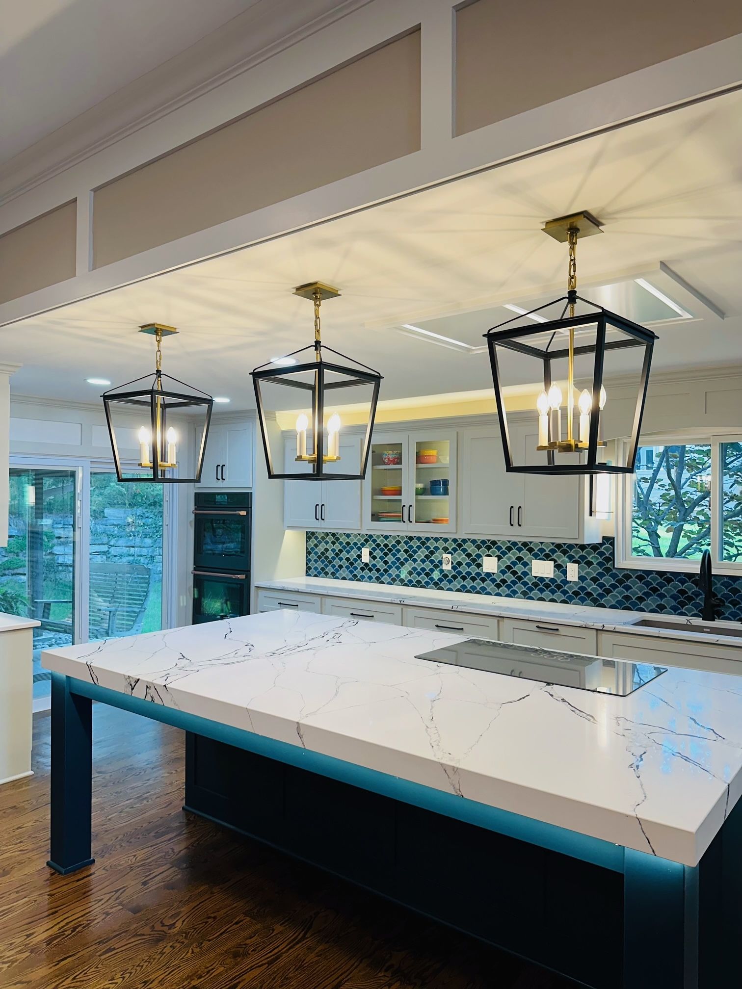 A kitchen with a large island and lanterns hanging from the ceiling.