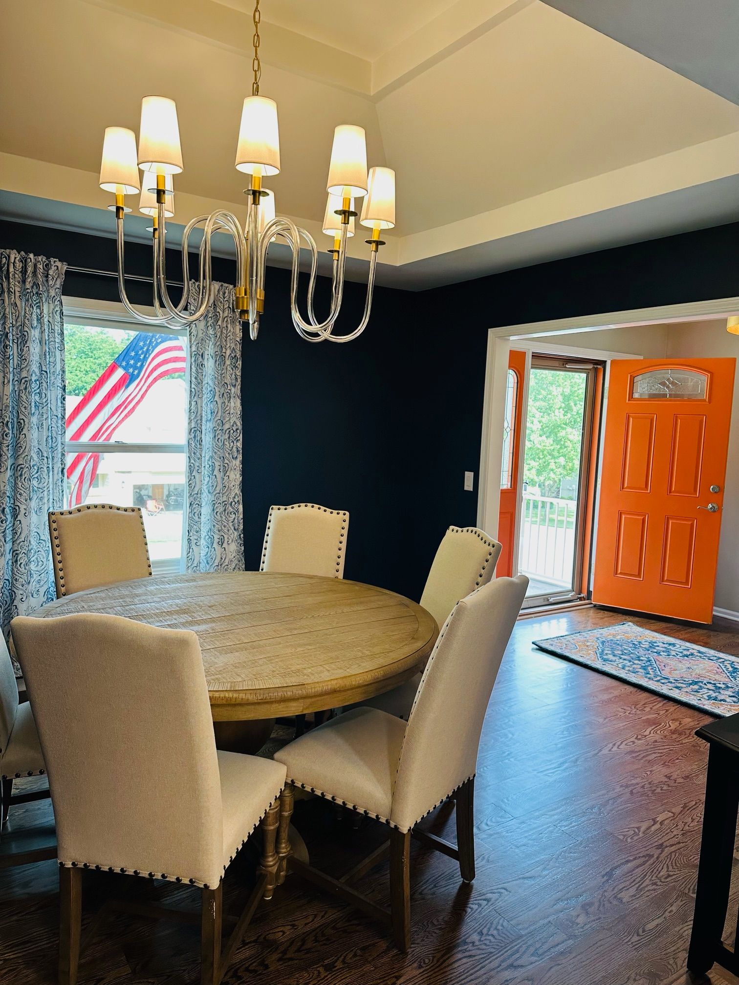 A dining room with a round table and chairs and a chandelier hanging from the ceiling.