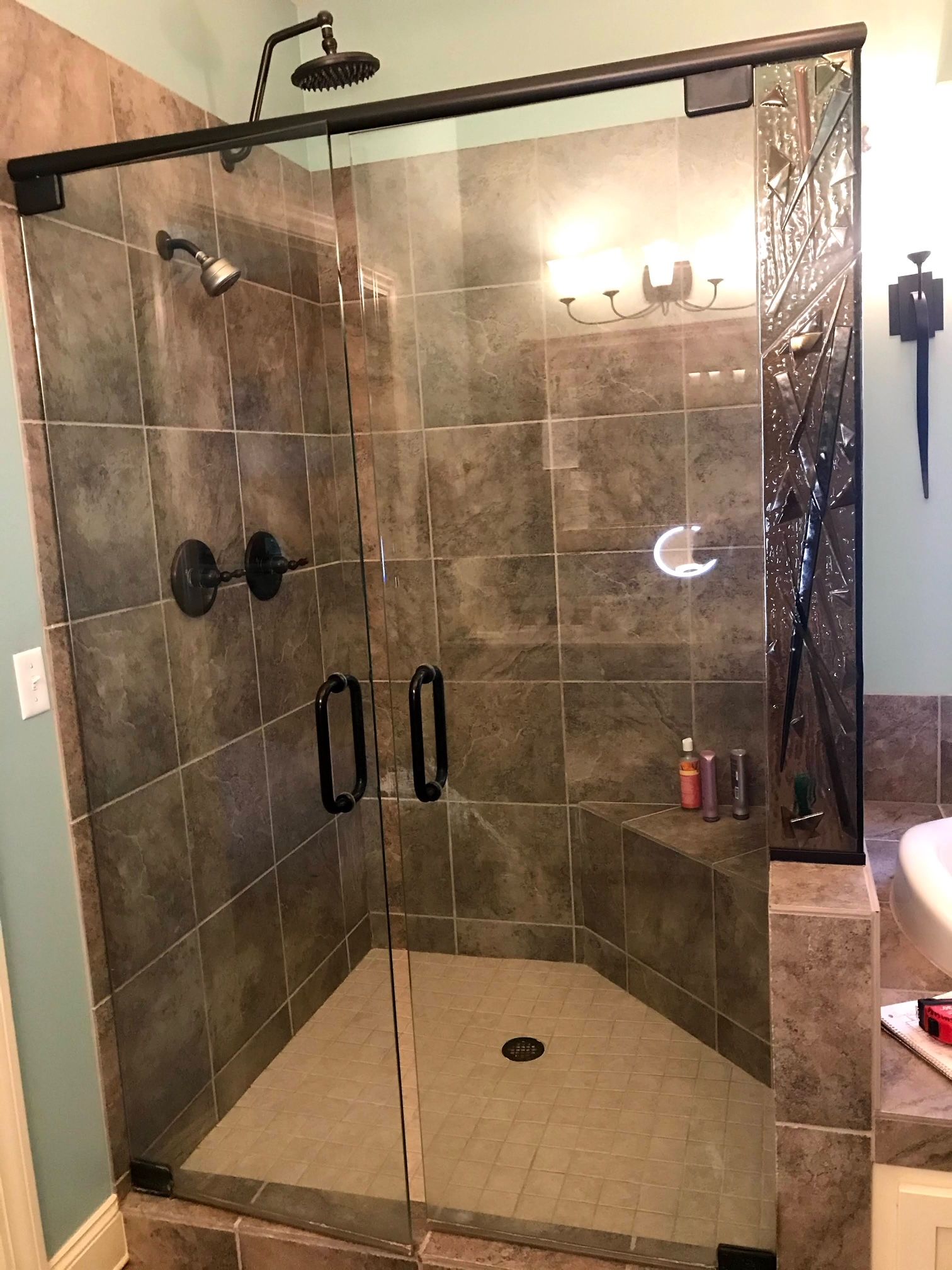 A bathroom with a walk in shower with a sliding glass door.