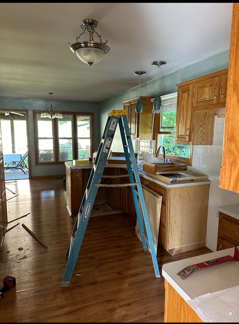 A ladder is sitting in the middle of a kitchen.