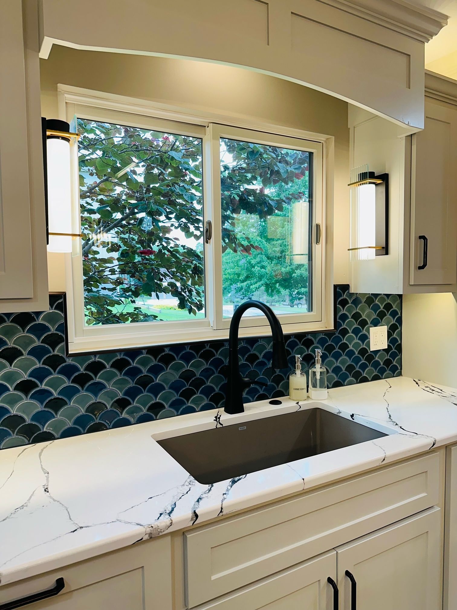 A kitchen with a sink , cabinets , and a window.
