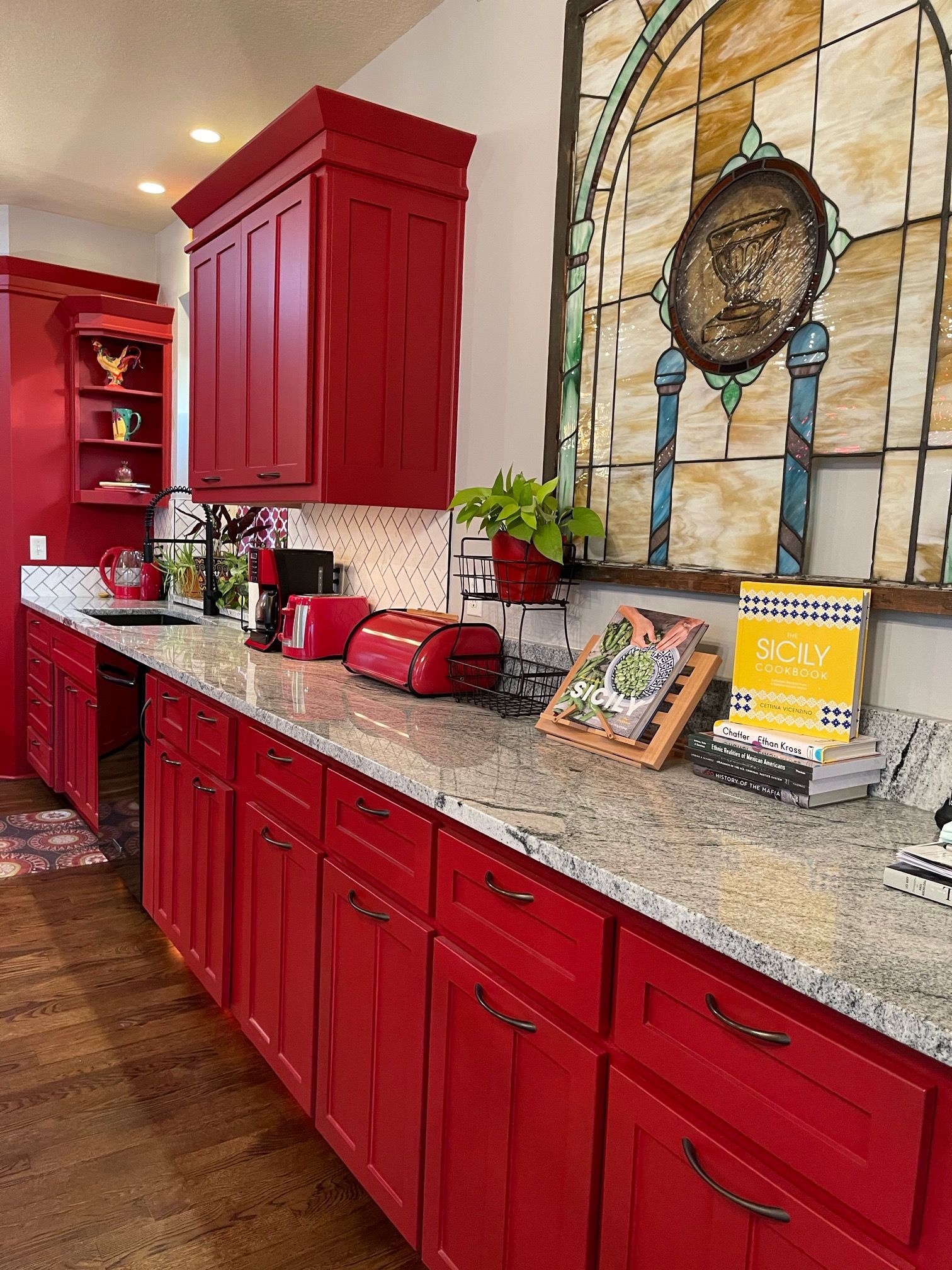 A kitchen with red cabinets and granite counter tops.