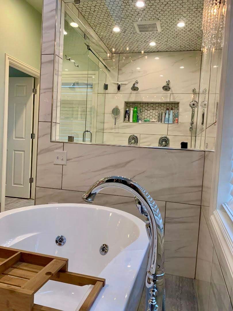 A bathroom with a bathtub and a large mirror.