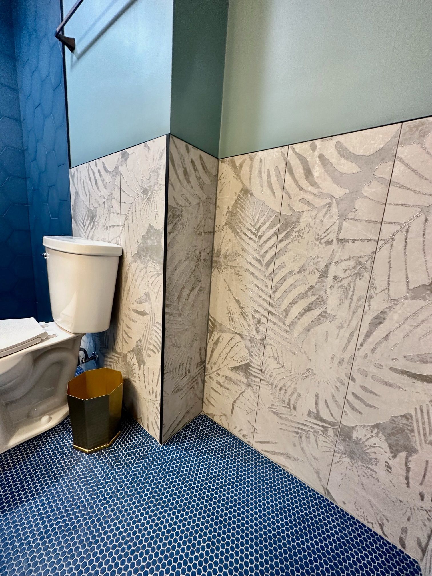 A bathroom with a toilet and a trash can on the floor.