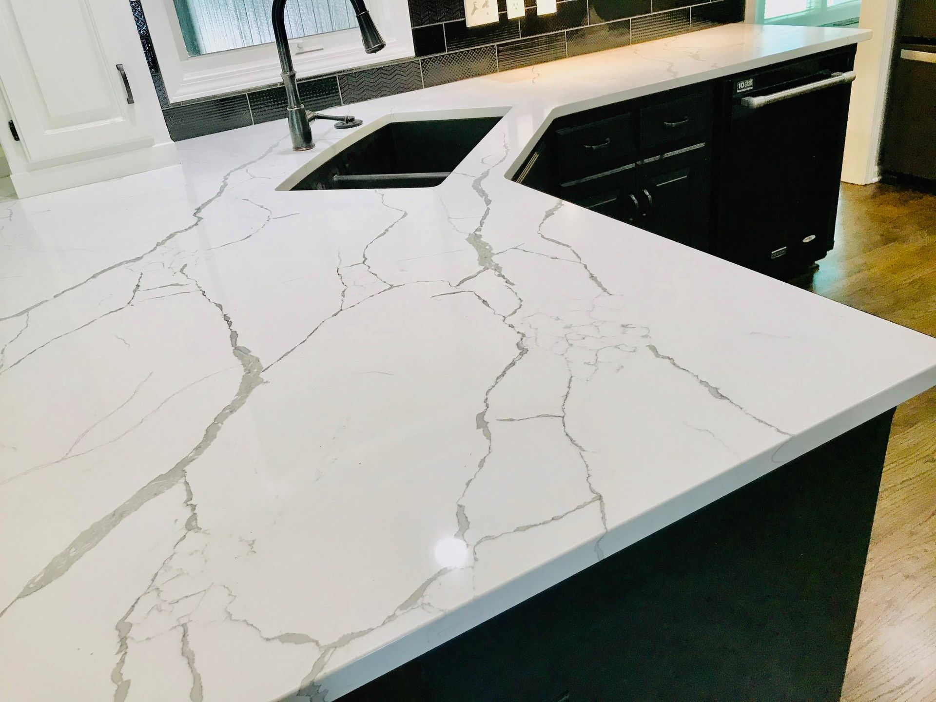 A kitchen with a white counter top and a black sink.