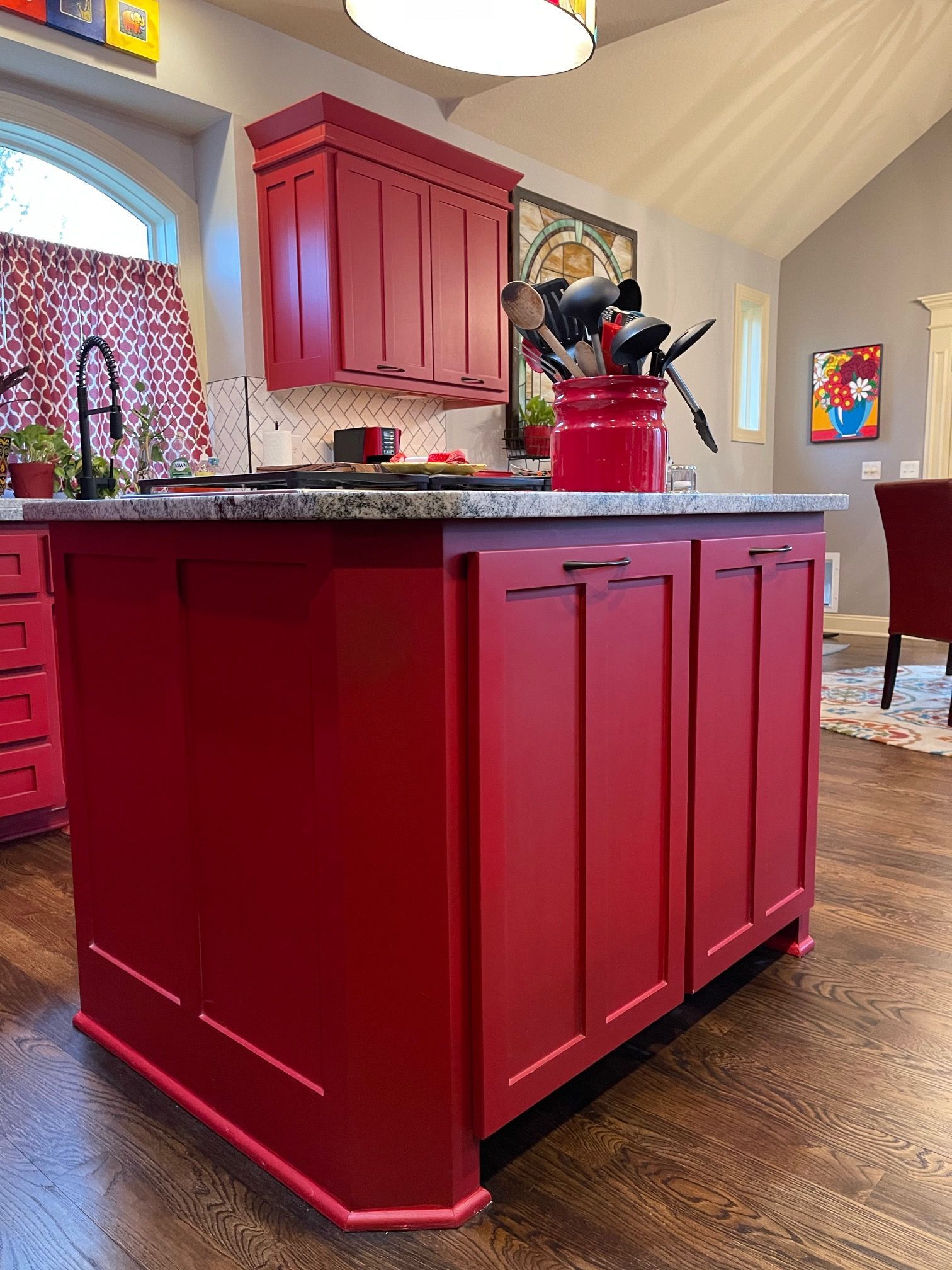A kitchen with red cabinets and a red pot on the counter.