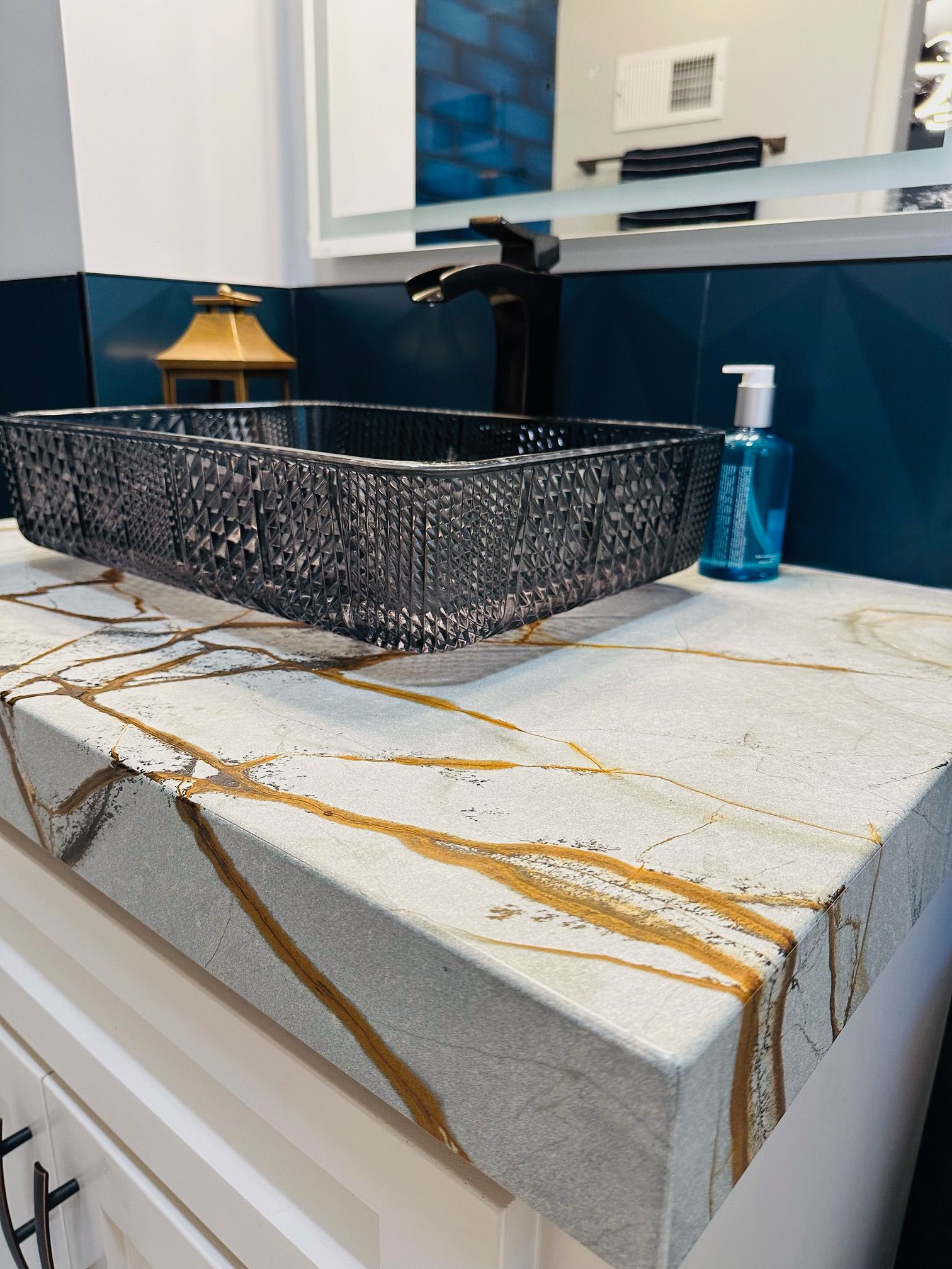 A bathroom counter with a sink and a soap dispenser