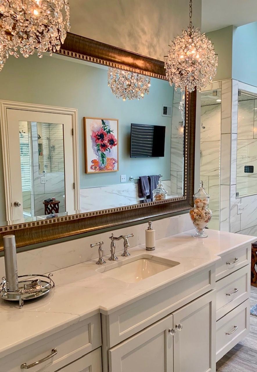 A bathroom with a sink , mirror and chandeliers.