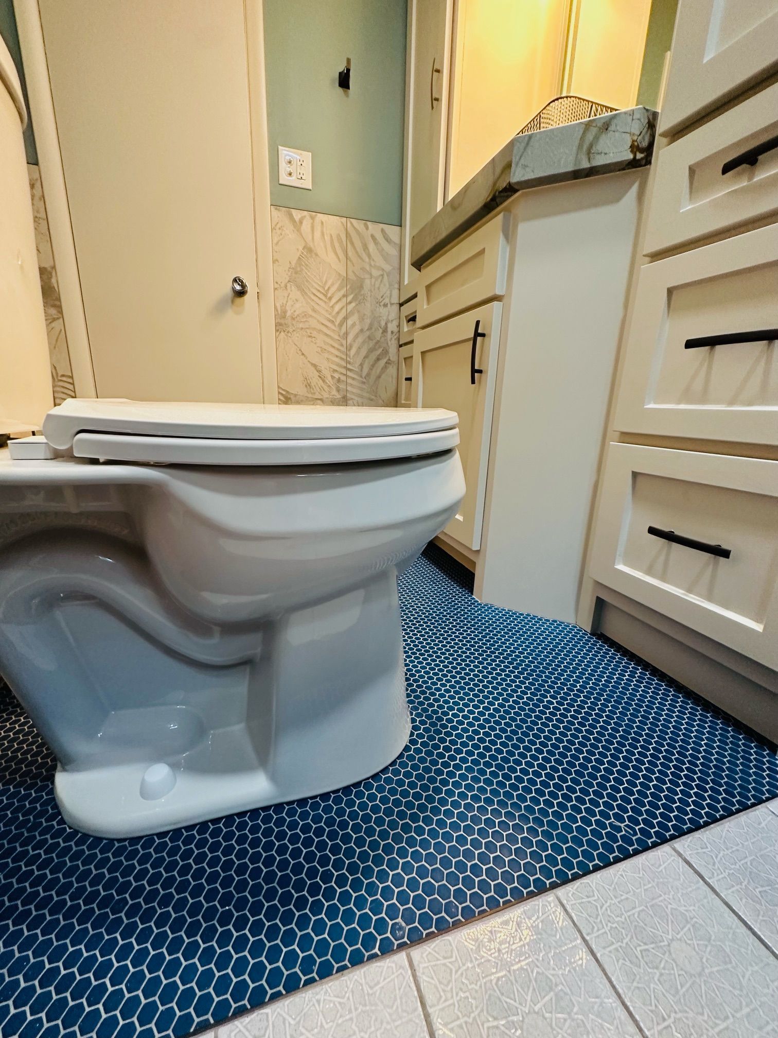 A white toilet is sitting on a blue tiled floor in a bathroom.