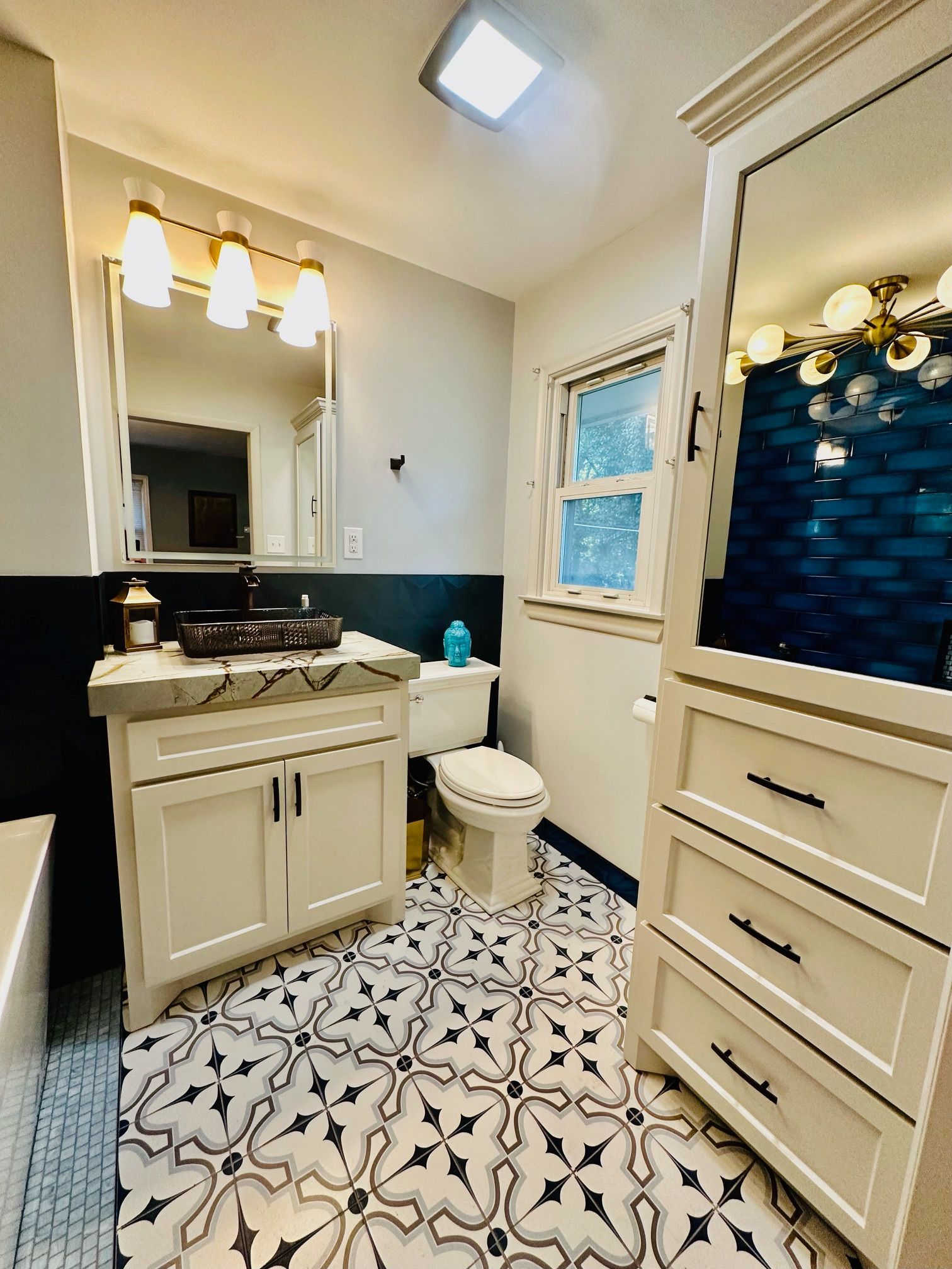 A bathroom with a sink , toilet , mirror and dresser.
