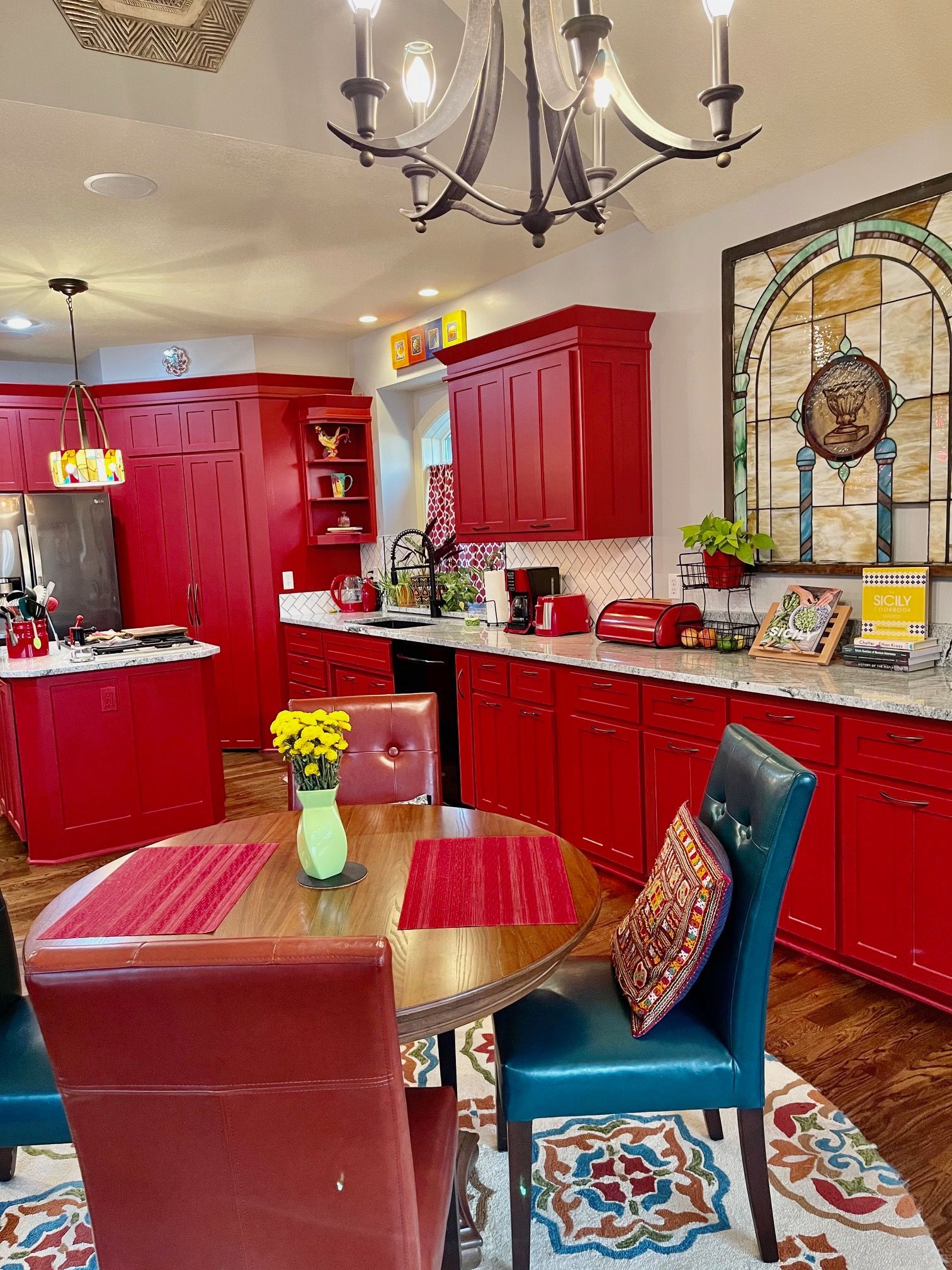 A kitchen with red cabinets , a table and chairs.