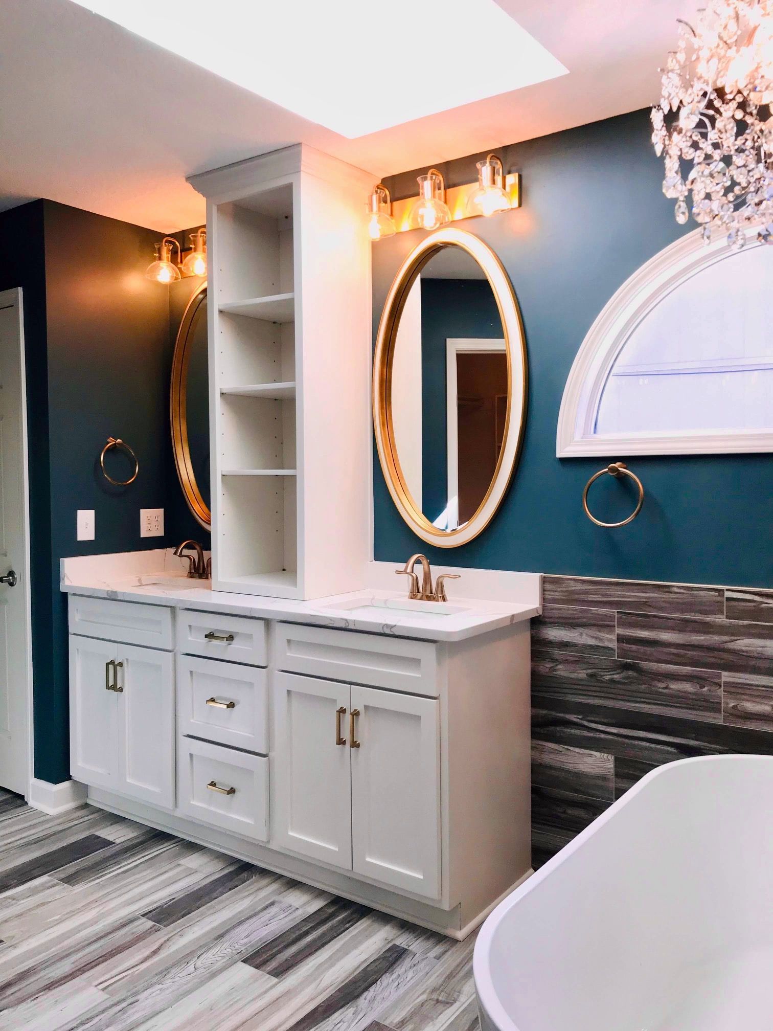 A bathroom with a bathtub , sink , mirror and skylight.