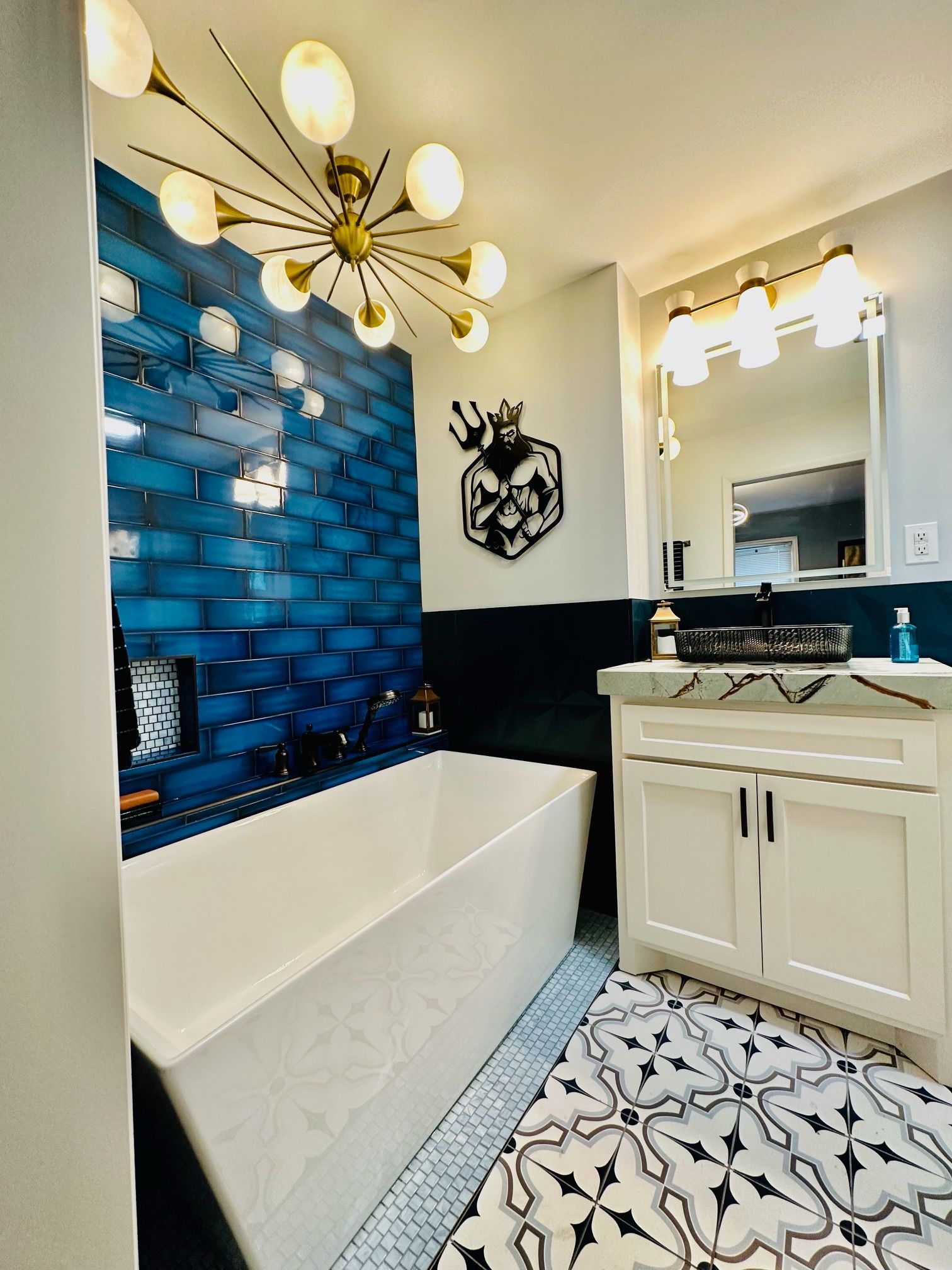 A bathroom with a bathtub , sink , mirror and blue tiles.