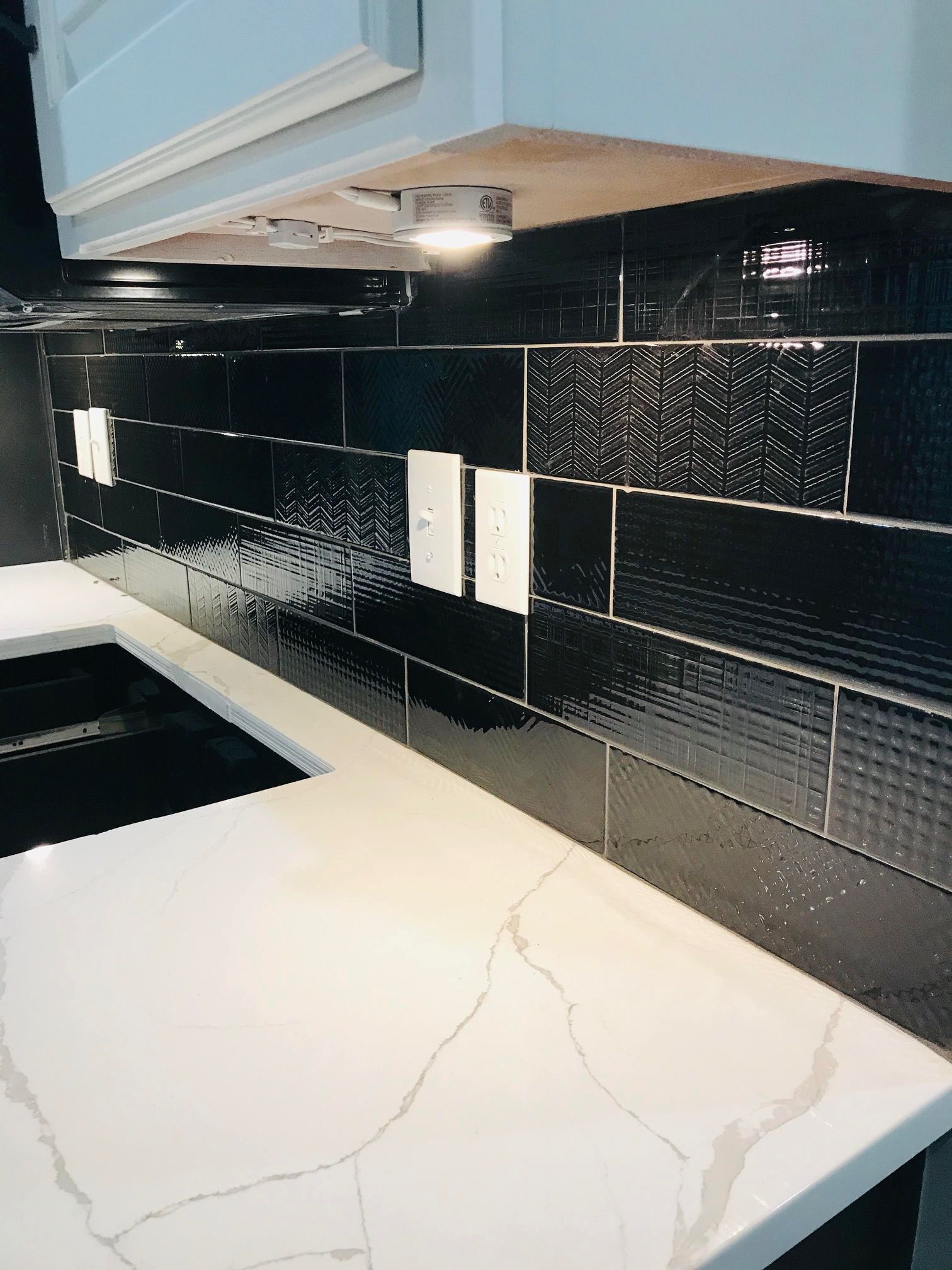A kitchen with black tiles and a white counter top