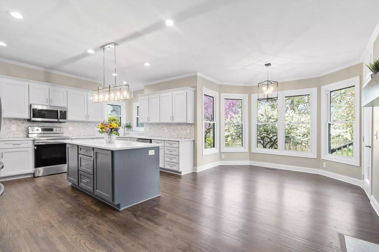A kitchen with a large island and lots of windows.