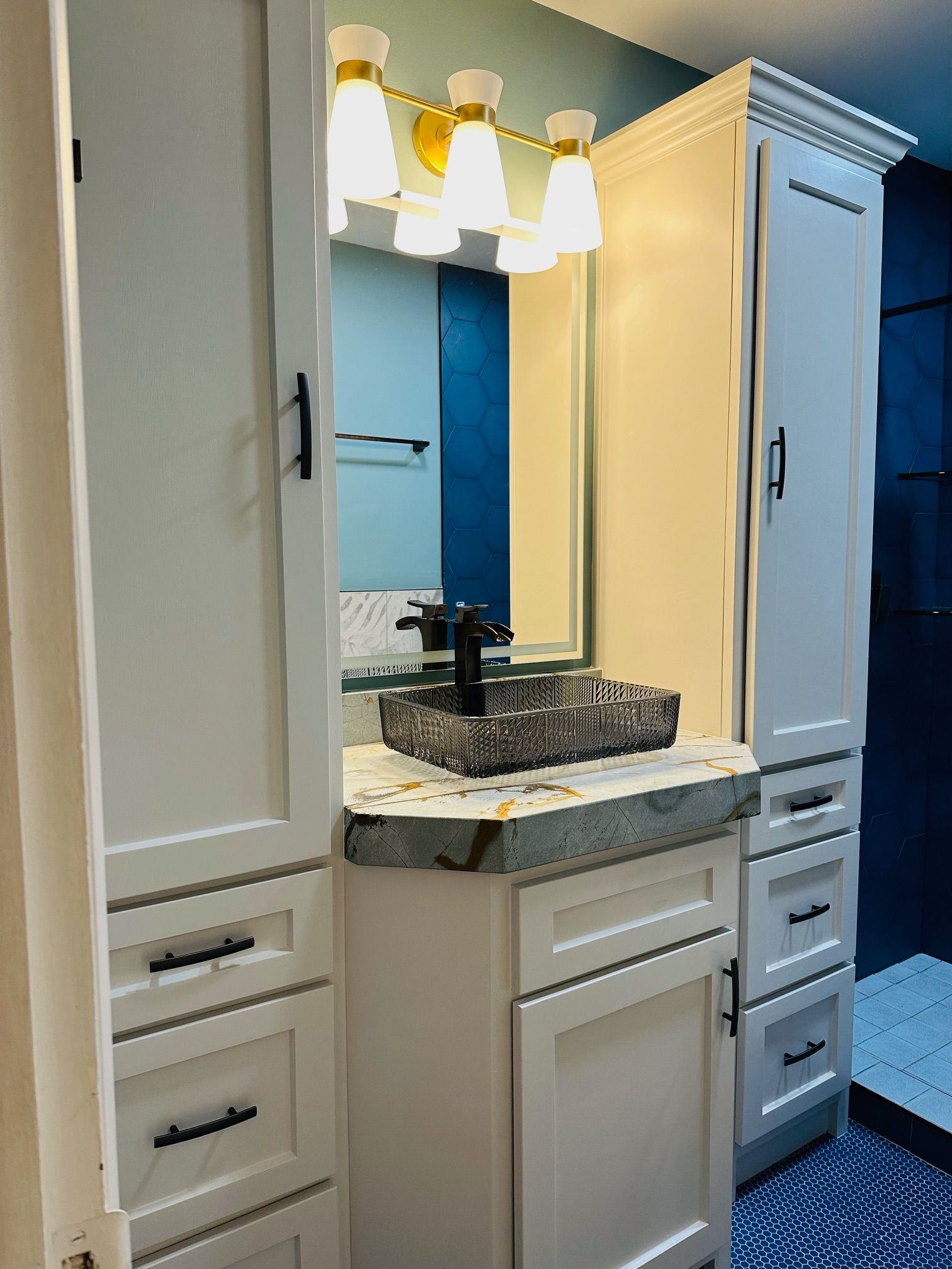 A bathroom with a sink , mirror , cabinets and drawers.