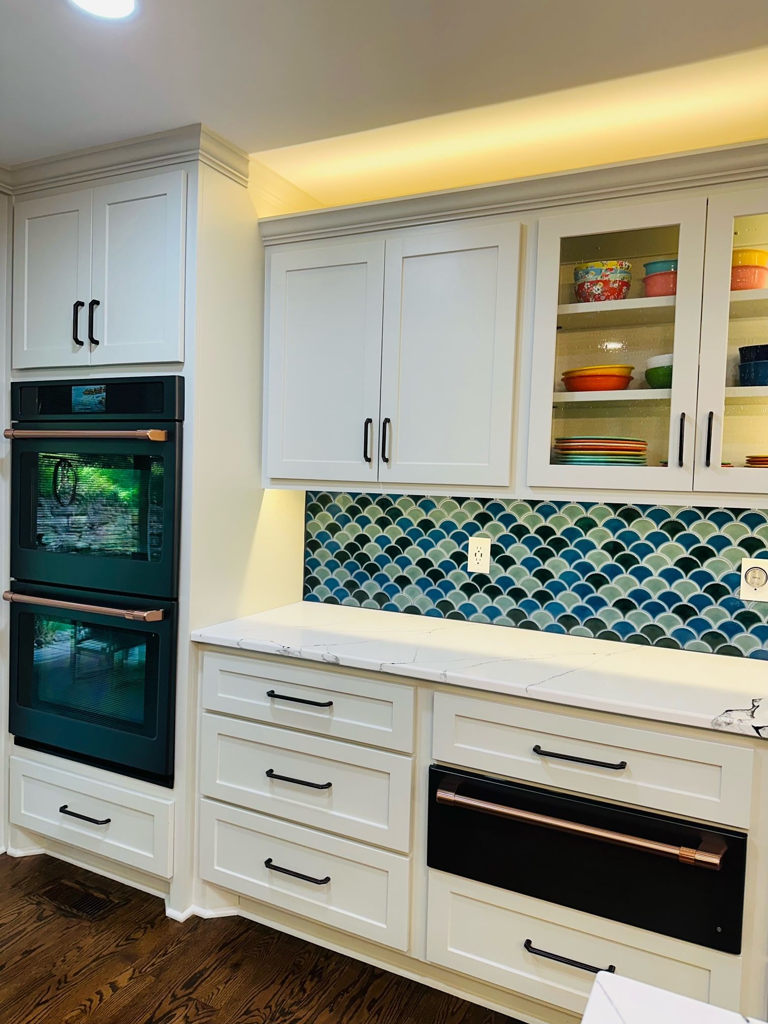 A kitchen with white cabinets , black appliances , and a mosaic tile backsplash.