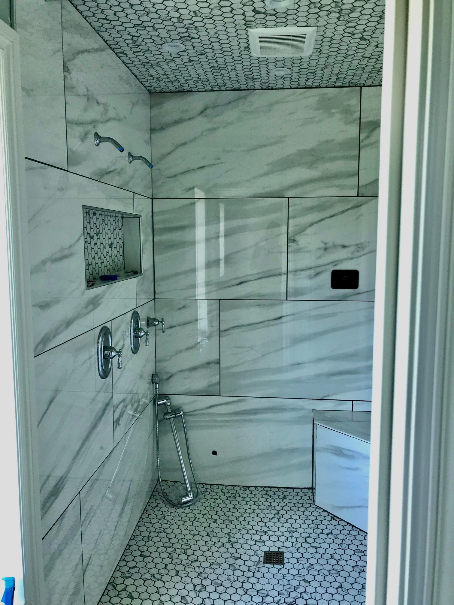A bathroom with marble tiles , a tub and a shower.