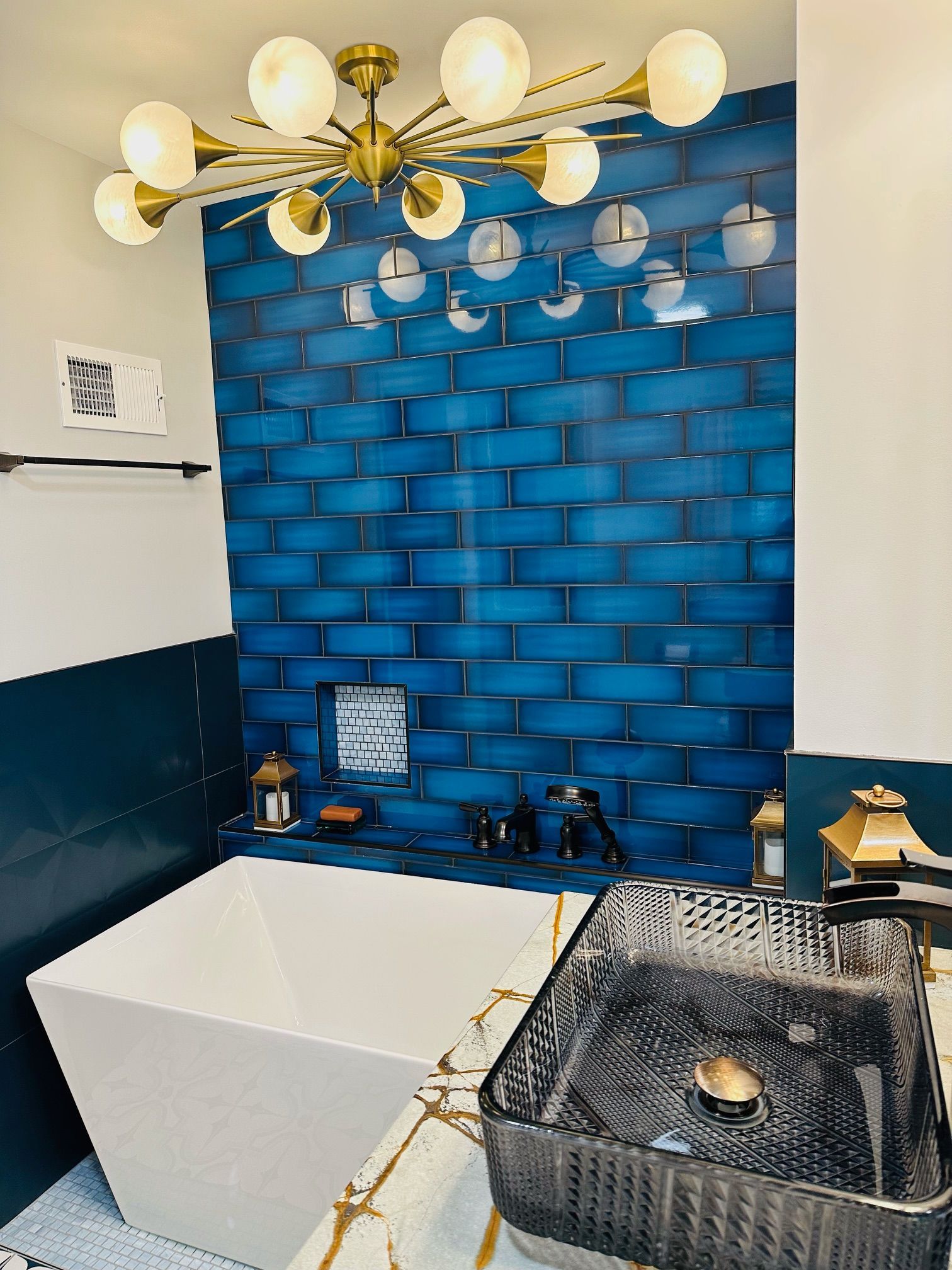 A bathroom with blue tiles , a sink , and a bathtub.