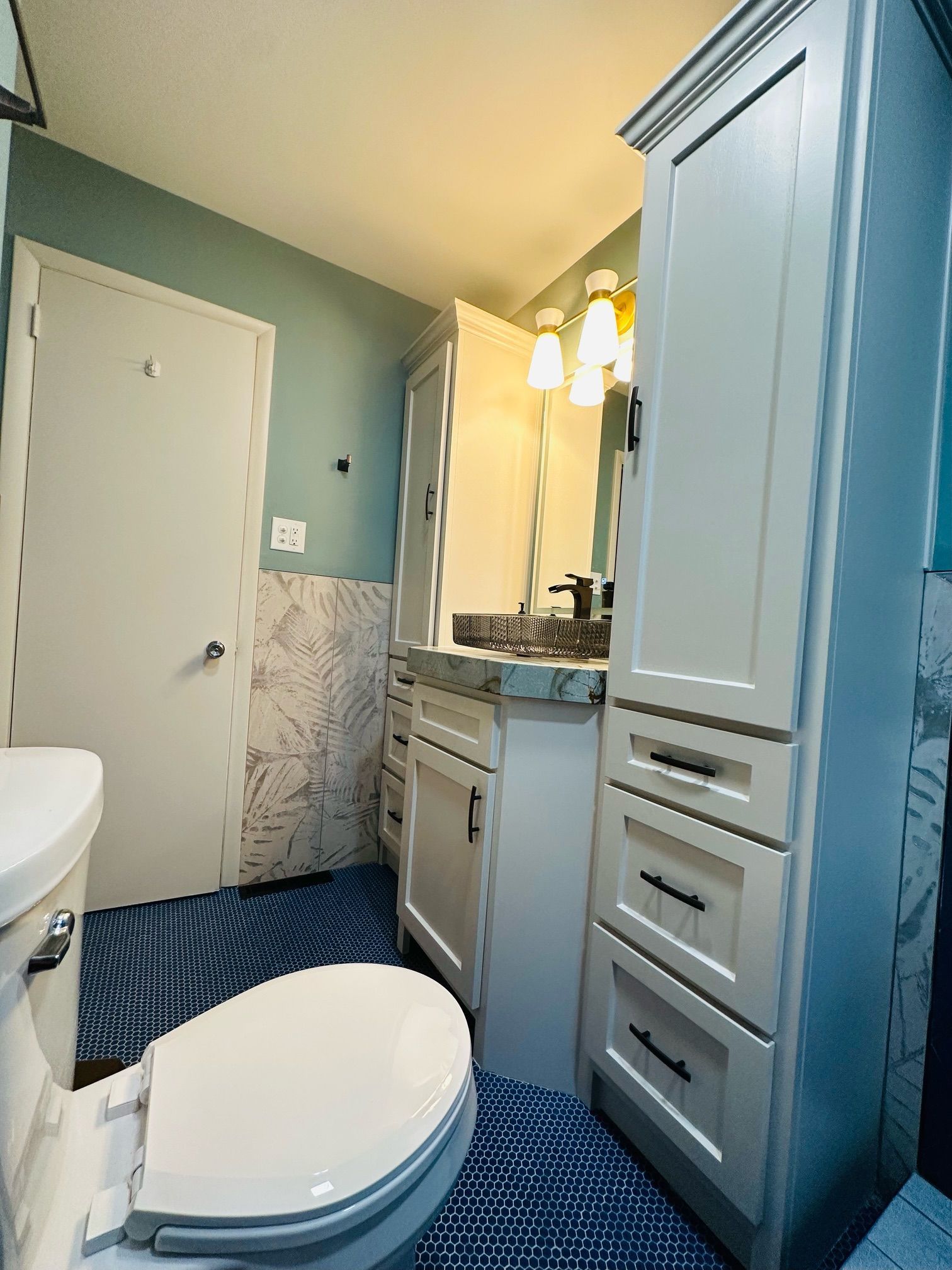 A bathroom with a toilet , sink and cabinets