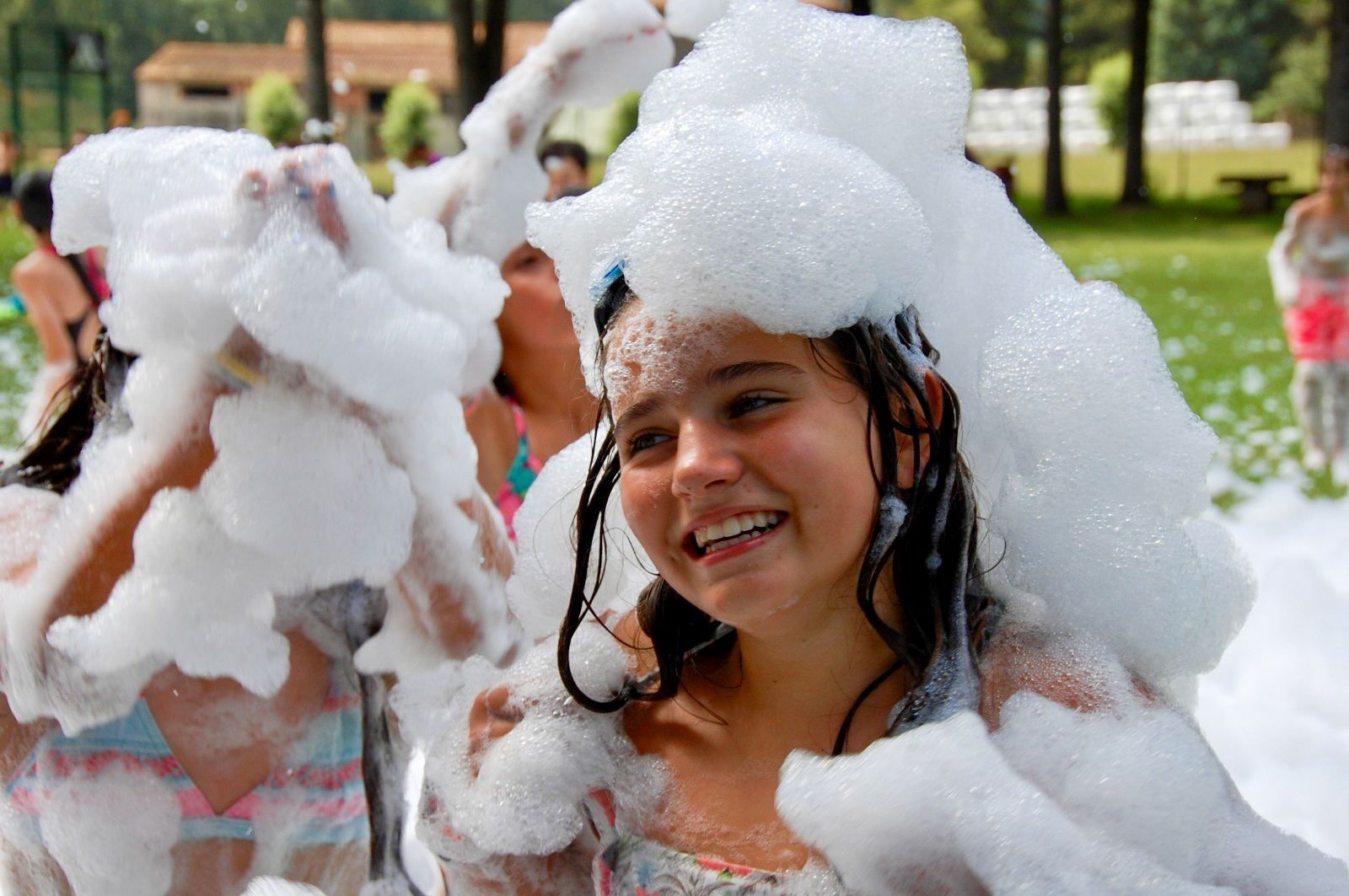 People covered in foam outdoors, smiling.