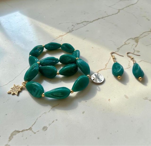 Teal bead necklace and matching earrings on a light marble surface