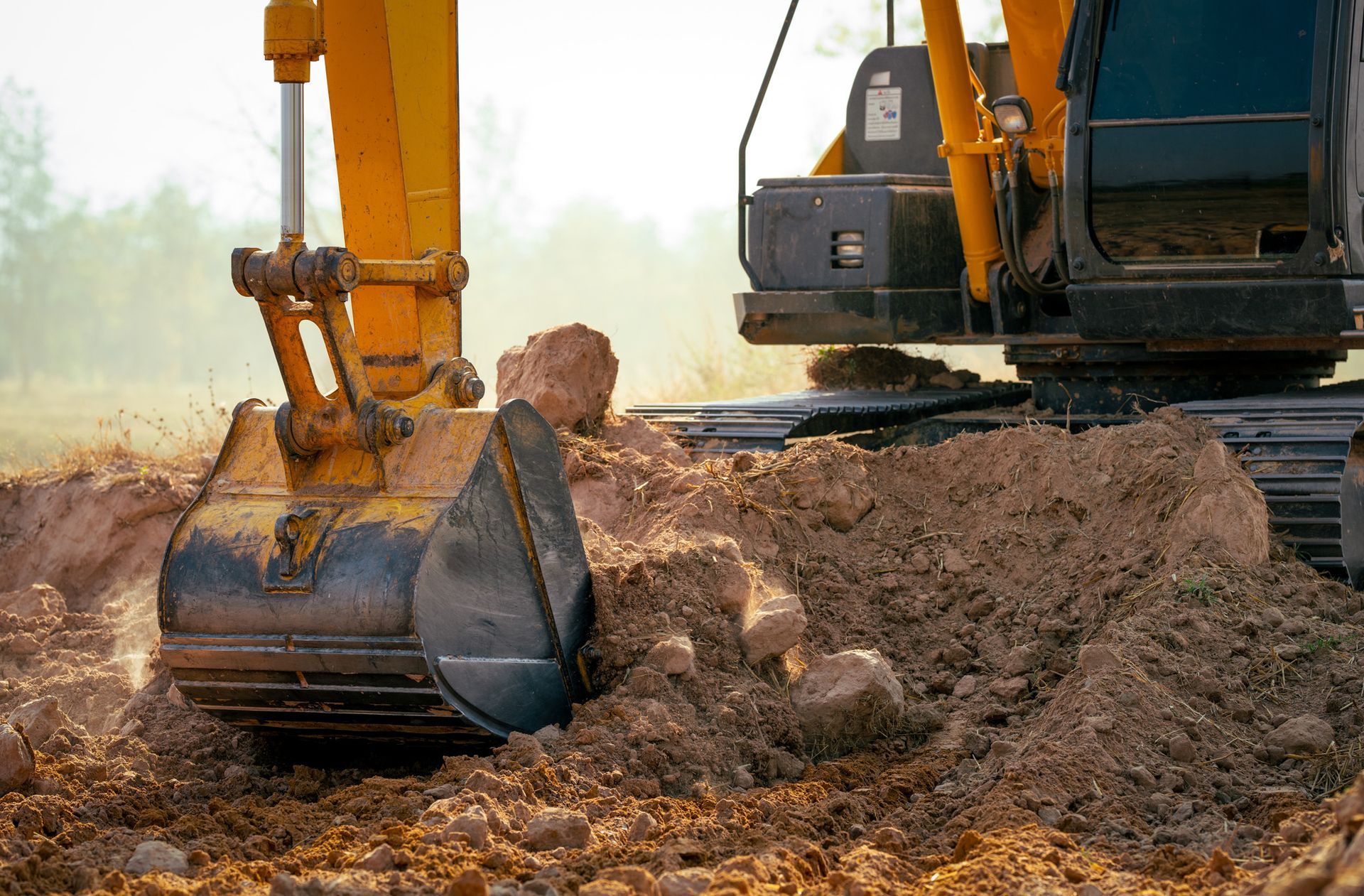 A yellow excavator is digging a hole in the dirt.