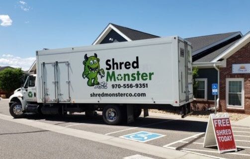 A shred monster truck is parked in front of a building.