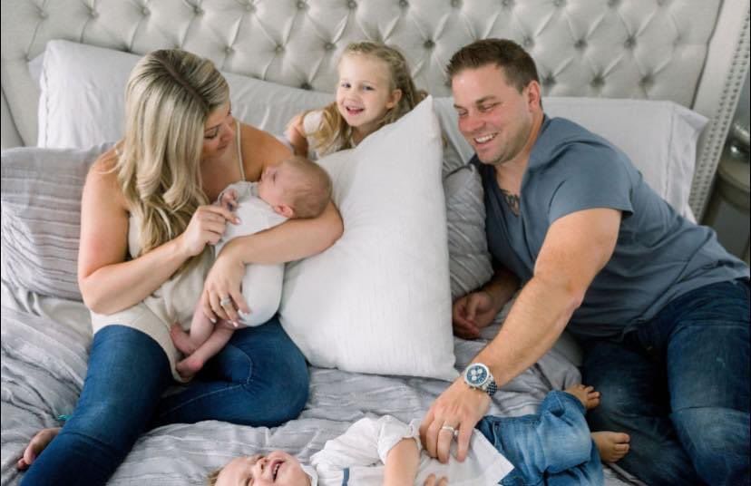A family is laying on a bed with two children.