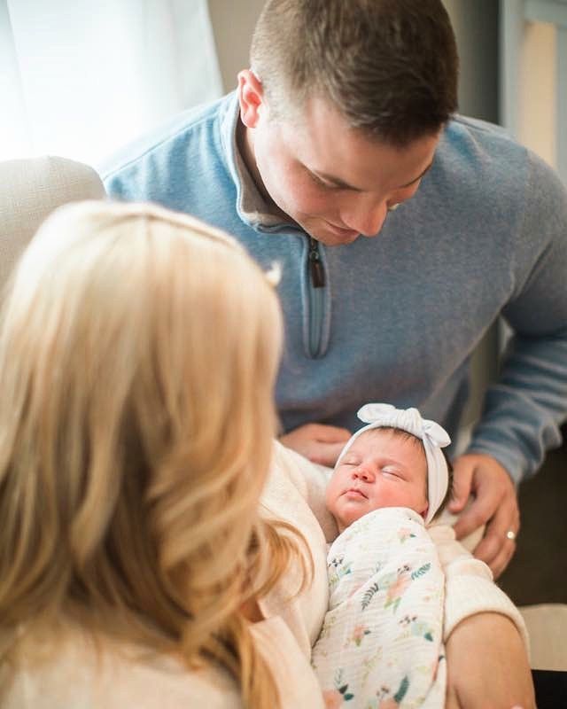A man and woman are holding a newborn baby in their arms.