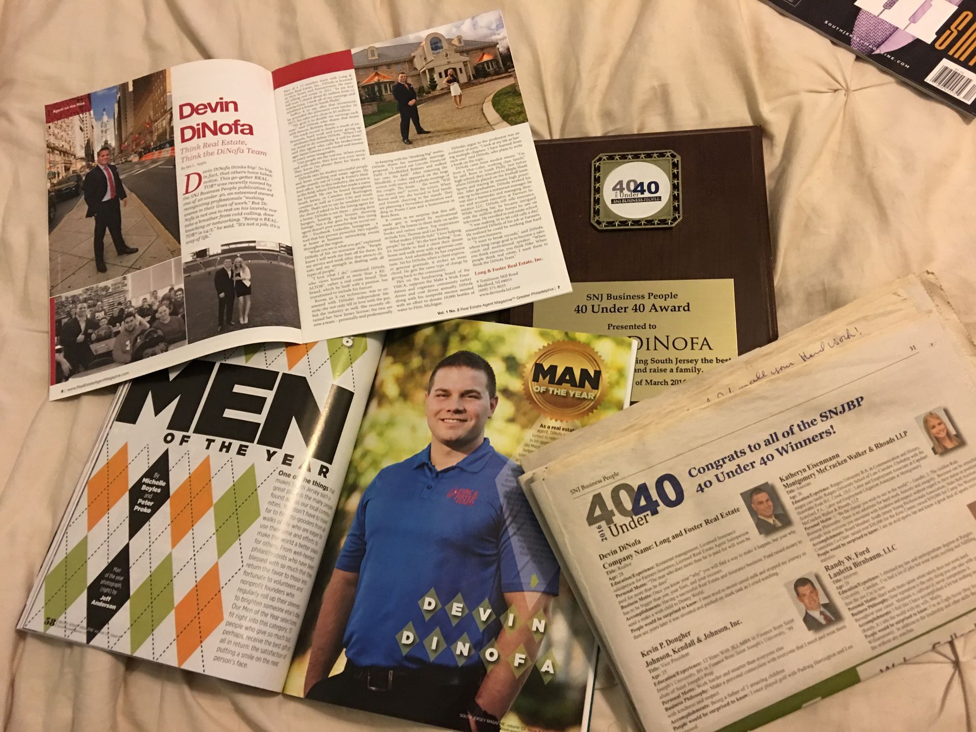 Several magazines including men of the year are laying on a bed