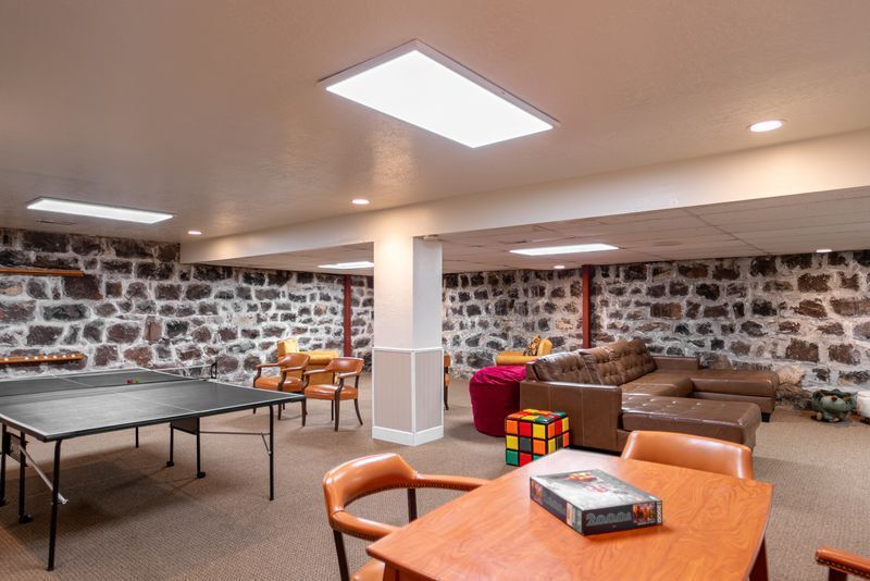 A basement with a table and chairs and a ping pong table.