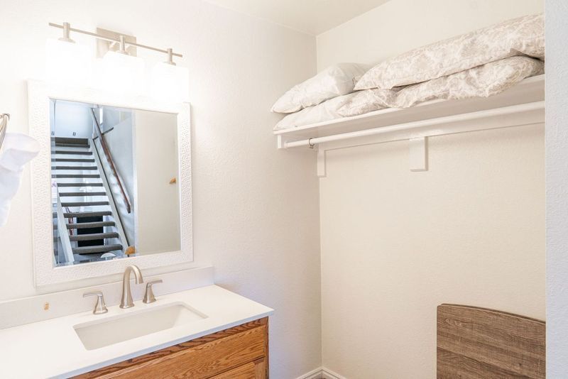 A bathroom with a sink , mirror and stairs.