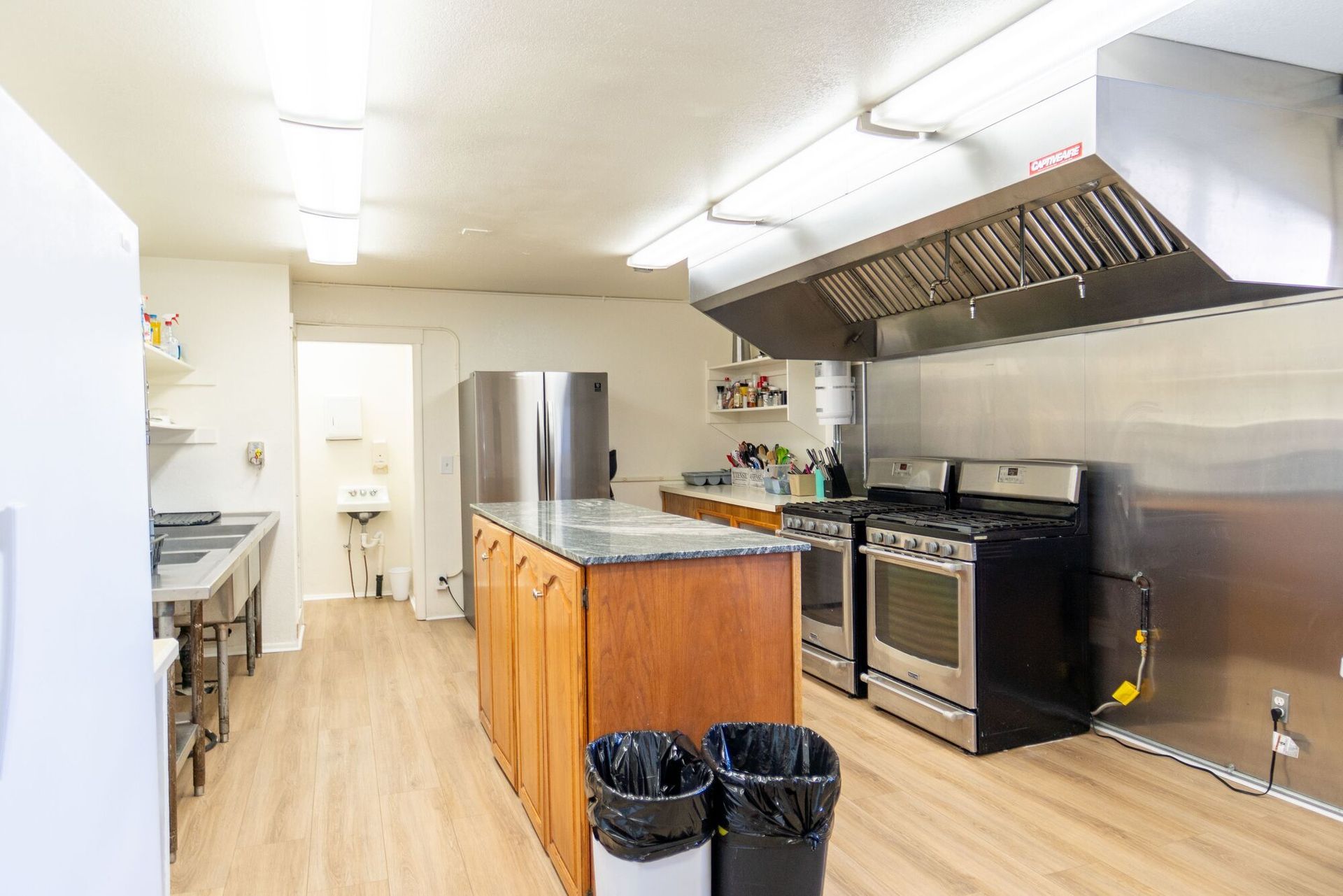 A large kitchen with stainless steel appliances and a large island in the middle.
